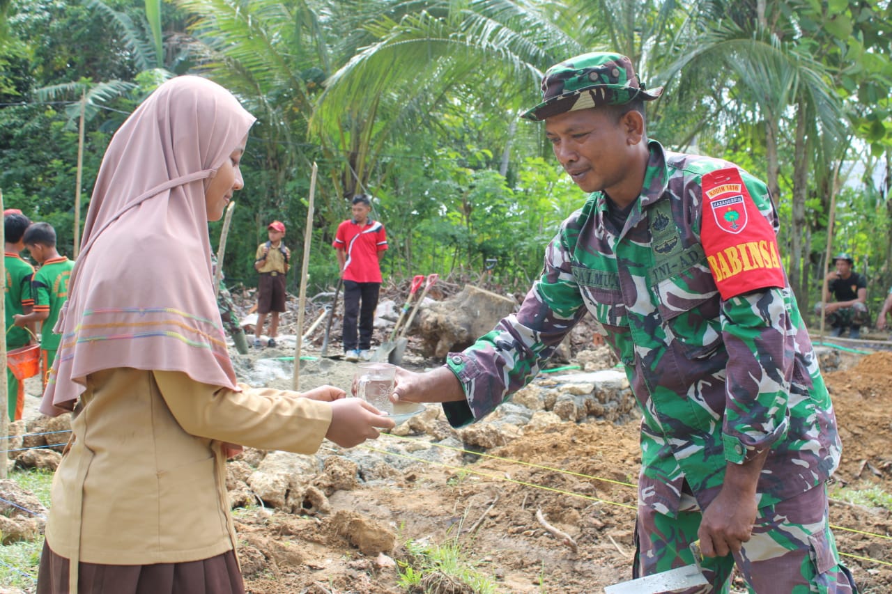 Dengan Keikhlasan dan Keceriaan, Pelajar SDN 5 Tiworo Tengah Menuangkan Minuman Kepada Anggota Satgas TMMD 123 Kodim 1416/Muna