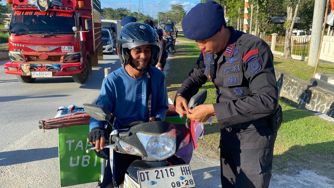 Semarak Merah Putih: Brimob Polda Sultra Bagikan dan Pasangkan Bendera kepada Pengguna Jalan Sambut HUT RI ke-80